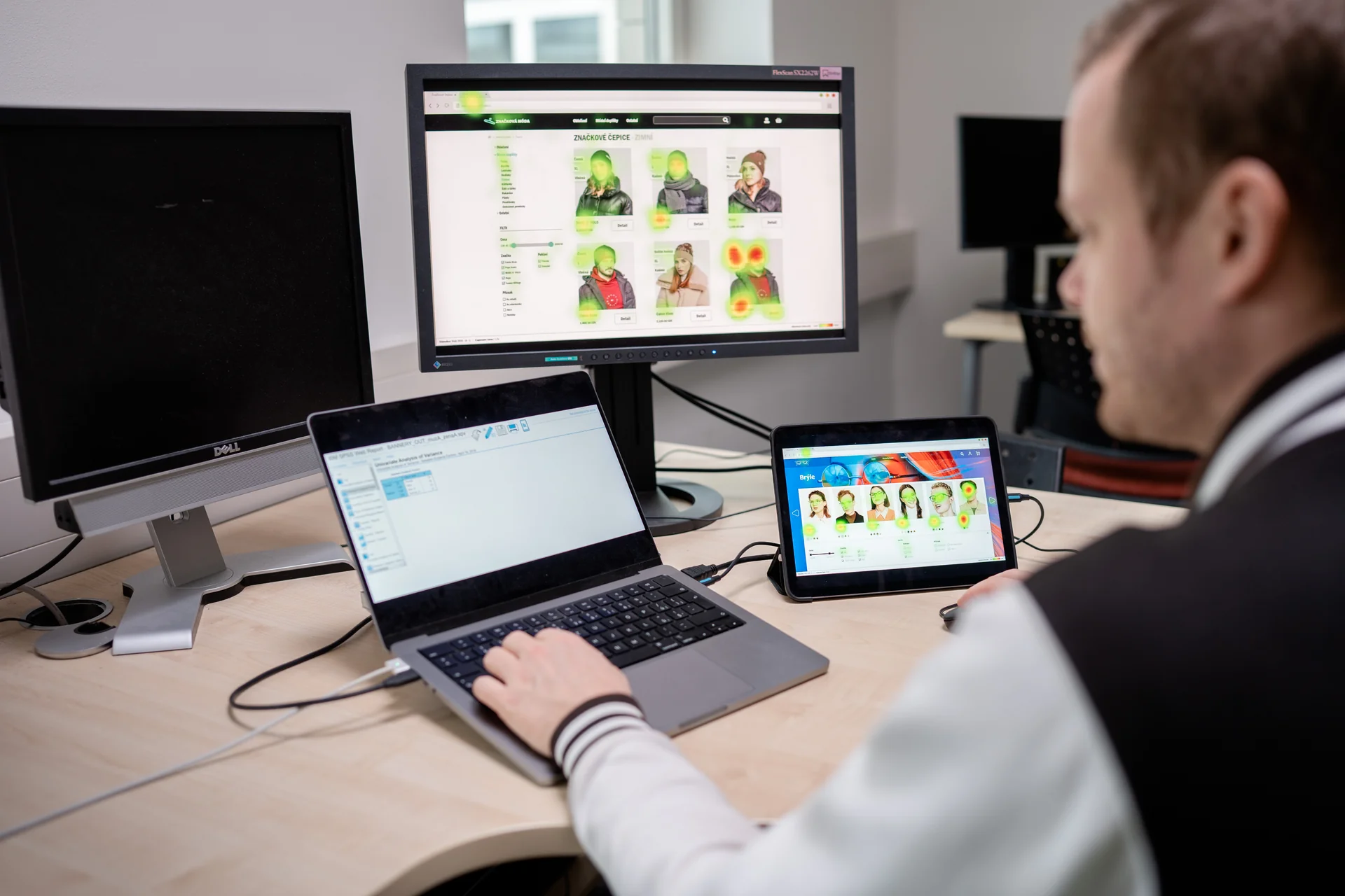Výzkumník UXMIND analyzuje eye-tracking data — na monitoru heatmapy vizuální pozornosti, na tabletu záznamy mimických výrazů respondentů